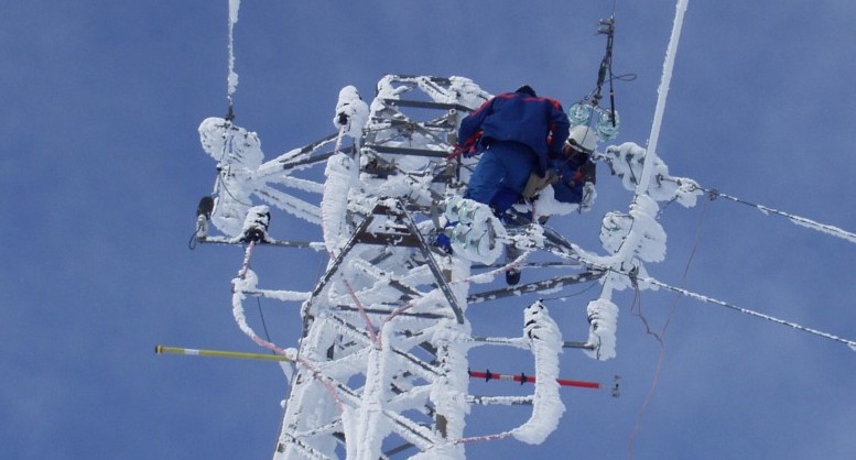 Tecnici dell'Enel su un traliccio innevato